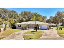 Inviting single-story home features a well-manicured lawn, long driveway, and mature landscaping at 1461 Helena Ct, Deltona, FL 32725