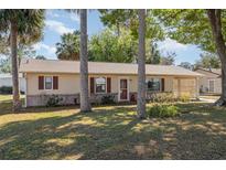 Charming single-story home featuring mature landscaping, vinyl siding, and an inviting front entrance with brick facade at 59 Aberdeen Cir, Leesburg, FL 34788