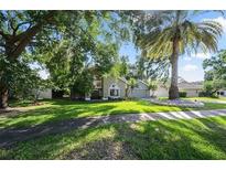 Beautifully landscaped front yard with a large palm tree and mature trees around the house at 703 E Lakeshore Dr, Ocoee, FL 34761