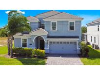 Charming two-story home with a well-manicured lawn and a paved driveway leading to a two-car garage at 8800 Interlocking Ct, Champions Gate, FL 33896