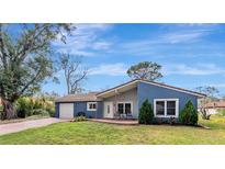 Charming blue single-story home boasts a well-manicured lawn and inviting front porch with seating area at 10455 Kingbrook Ln, Orlando, FL 32821