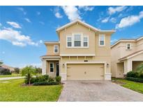 Inviting two-story home featuring a well-manicured lawn and a spacious two-car garage at 1100 Downswing Pl, Davenport, FL 33896