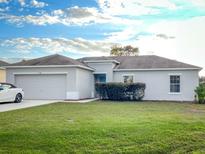 Well-maintained single-story home with green lawn, neutral paint, and attached two-car garage at 734 Fraser Ct, Kissimmee, FL 34759