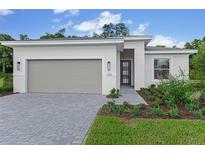 Beautiful one-story home with a gray garage door, gray brick paver driveway, and inviting landscaped front yard at 1251 Cresswind Blvd, Deland, FL 32724