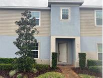 Charming townhouse featuring a light blue and tan exterior, complemented by a well-maintained front yard and inviting entrance at 522 Grace Ct, Davenport, FL 33837