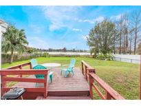 Outdoor deck overlooking a serene lake, furnished with a table, chairs, and grill at 5380 Barton Dr, Orlando, FL 32807