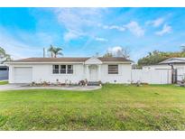 Charming single-story home with a white exterior, well-maintained lawn and flower beds at 5380 Barton Dr, Orlando, FL 32807