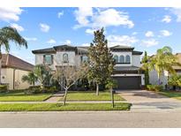 Elegant two-story home with a manicured lawn, paver driveway, tile roof, and a beautiful architectural design at 8515 Morehouse Dr, Orlando, FL 32836
