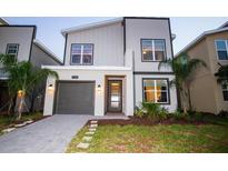 Attractive two-story home featuring a modern color palette and well-manicured landscaping at 8988 Cabot Cliffs Dr, Champions Gate, FL 33896