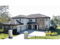 Elegant two-story stucco home featuring a three-car garage, stone accents, and well-manicured landscaping at 9526 Lake Hugh Dr, Gotha, FL 34734