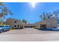 A daytime exterior view of a charming two-story condo building with covered parking and lush landscaping at 1428 Oak Pl # J, Apopka, FL 32712