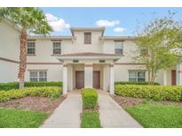 Inviting townhome exterior with manicured landscaping, featuring a well-maintained lawn and decorative shrubbery at 1569 Plunker Dr, Davenport, FL 33896