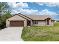 Charming brick home featuring an attached two-car garage and a well-maintained front lawn at 1811 Springwood Ln, Deltona, FL 32725