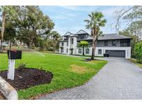 View of the home's exterior with a well-manicured lawn, sprinkler system, and paver driveway at 2721 Ingeborg Ct, Windermere, FL 34786