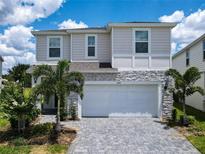 Charming two-story home showcasing a two-car garage, paver driveway, and well-maintained landscaping at 3401 Lilac Way, Davenport, FL 33897