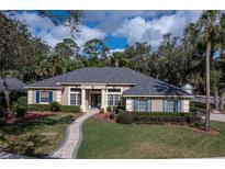 Beautiful one-story home with manicured landscaping, blue shutters, neutral stucco, and a brick walkway leading to the front door at 4978 Fawn Ridge Pl, Sanford, FL 32771