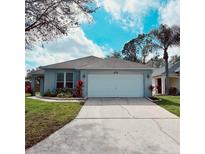 Charming single-story home featuring a two-car garage, well-maintained lawn, and vibrant landscaping at 109 Grosvenor Loop, Davenport, FL 33897