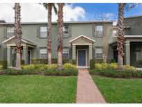 Charming townhome features manicured landscaping, palm trees, and a welcoming brick pathway to the front door at 14849 Driftwater Dr, Winter Garden, FL 34787