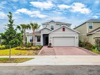 Charming two-story home boasts a well-maintained lawn, brick driveway, and a two-car garage at 603 Fortuna Dr, Davenport, FL 33837