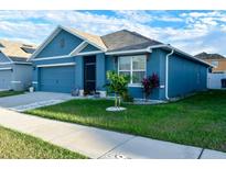 Charming single-story home features blue siding, a well-manicured lawn, and an attached garage at 756 Kindred Ln, Auburndale, FL 33823