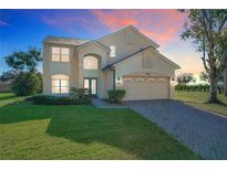 Two story home featuring an arched entryway, attached two car garage, and manicured landscaping at 8438 Diamond Cove Cir, Orlando, FL 32836