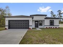 Charming single-story home featuring a modern design, black trim, a two-car garage, and freshly planted landscaping at 13817 Sw 43Rd Cir, Ocala, FL 34473