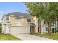 Inviting two-story home featuring a manicured lawn, cream-colored paint, and a convenient two-car garage at 2362 Blossomwood Dr, Oviedo, FL 32765