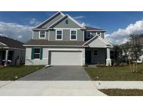 Charming two-story home featuring gray siding, a two-car garage, and a well-manicured lawn at 4972 Lyric Dr, Mascotte, FL 34753