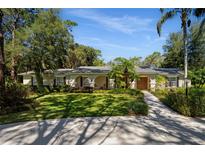 Charming single-story home with a manicured lawn, mature trees, and a welcoming front entrance at 11 Stone Gate S, Longwood, FL 32779