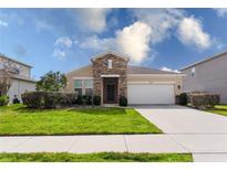 Charming single-Gathering home featuring a stone facade, manicured lawn, and a two-car garage at 4053 Brookshire Cir, Eustis, FL 32736