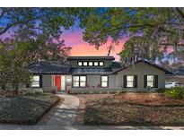 Charming single-story home with a red door, brick walkway, and well-maintained landscaping at 4114 Lake Mira Dr, Orlando, FL 32817