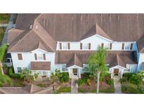 Aerial view of light blue townhomes with brown shutters and roofs surrounded by sidewalks and green landscaping at 5354 Diplomat Ct # 106, Kissimmee, FL 34746