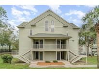 Two-story condo building with stairs leading to the second-floor balconies and light green siding at 6166 Westgate Dr # 302, Orlando, FL 32835