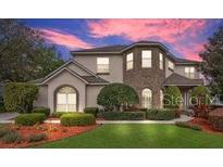 Charming two-story home featuring a brick facade, lush green lawn, and beautiful landscaping at 1601 Billingshurst Ct, Orlando, FL 32825