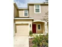 Two-story home featuring neutral stucco, red door, tan garage door, and manicured landscaping at 3587 Davenport Creek Ct, Kissimmee, FL 34746