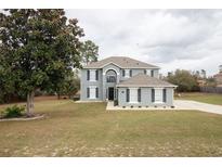 Two-story home featuring a manicured front yard and a symmetrical facade with dark shutters on all windows at 4191 Sw 110Th Ln, Ocala, FL 34476