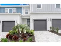 Modern townhome with gray garage door, blue trim, updated landscaping and paved driveway at 7838 Spectrum Dr, Kissimmee, FL 34747