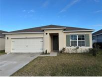 Charming single-story home featuring a two-car garage, landscaped yard, and neutral-colored exterior at 1463 Riverboat Dr, Kissimmee, FL 34744
