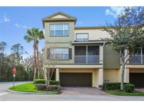 Three-story townhome with a two-car garage, mature landscaping, and a screened-in porch at 2604 Grand Central Pkwy # 12, Orlando, FL 32839