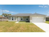 Inviting single-story home featuring a two-car garage, well-maintained lawn, and neutral color palette at 2765 Sw 140Th Pl, Ocala, FL 34473