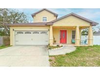 Inviting yellow two-story home featuring a bright red front door and attached one car garage at 410 South Hudson St, Orlando, FL 32835