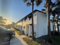 Low angle view of a two-story condo building with white walls and many palm trees around the building at 4419 S Semoran Blvd # 7, Orlando, FL 32822