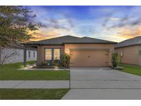 Charming single-story home featuring a two-car garage, landscaped yard, and inviting front entrance at sunset at 455 Eaglecrest Dr, Haines City, FL 33844