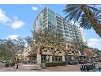 Modern condo building featuring expansive glass windows, street-level shops and restaurants, palm trees and city views at 101 S Eola Dr # 1001, Orlando, FL 32801