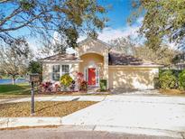 Charming single-story home with a red front door, manicured landscaping, and a two car garage at 1121 Magnolia Blossom Ct, Apopka, FL 32712