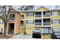 Front exterior of a yellow two-story apartment building with a black truck in the driveway at 5017 City St # 1932, Orlando, FL 32839