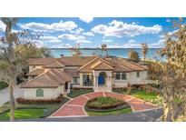 Stunning lakefront home with a circular driveway, lush landscaping, and a blue front door at 9243 Point Cypress Dr, Orlando, FL 32836