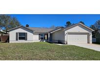 Charming single-story home with a well-maintained lawn and attached two-car garage on a sunny day at 12151 Goldenstar Ln, Clermont, FL 34711