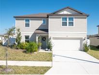 Charming two-story home with neutral siding, manicured lawn, and attached two-car garage at 1217 Michelangelo Ln, Winter Haven, FL 33884