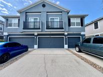 Three-story townhouse with three garages and balconies, painted in gray tones, and driveway at 6640 S Goldenrod Rd # 118B, Orlando, FL 32822